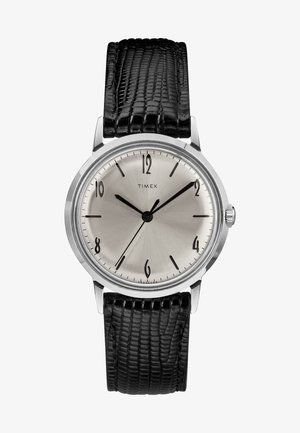 Srebrna ura Timex s črnim usnjenim paščkom z teksturo lisice, črnimi oznakami ur in kazalci, ki kažejo čas 10:08:37.