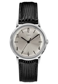 Montre Timex avec un cadran argenté, des index noirs et un boîtier en acier. Elle est dotée d'un bracelet en cuir noir texturé. Design simple et élégant.