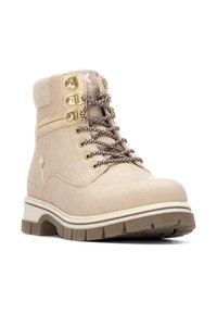 Botín de tobillo beige hecho de gamuza con ojales en tono dorado y cordones marrones. Cuenta con una suela gruesa con un tread texturizado para mayor agarre.