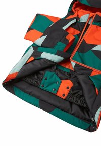 Giacca colorata con motivi geometrici in verde, nero, arancione e azzurro; presenta una chiusura frontale con zip e bottoni a pressione.