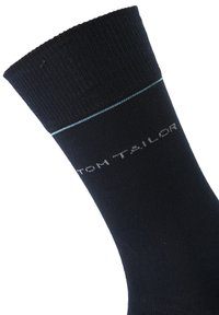Calcetines de algodón azul marino con textura acanalada, que presentan una raya horizontal azul claro y el texto blanco "Tom Tailor" tejido en el material.