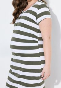 Vestido a rayas con franjas alternas de verde oliva y blanco, mangas cortas, escote redondeado y fruncidos laterales para una forma adicional.