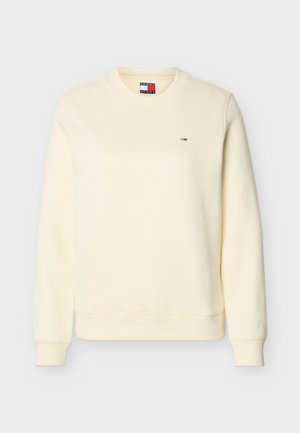 Krém színű hosszú ujjú, kerek nyakú pulóver kis Tommy Hilfiger logóval a bal mellrészen, bordázott mandzsettával és szegéllyel.