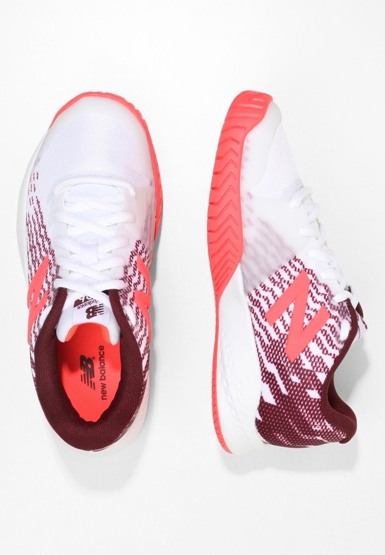 White athletic shoes with red accents and mesh upper. Features a textured sole and a patterned design on the sides. Logo on heel and tongue.