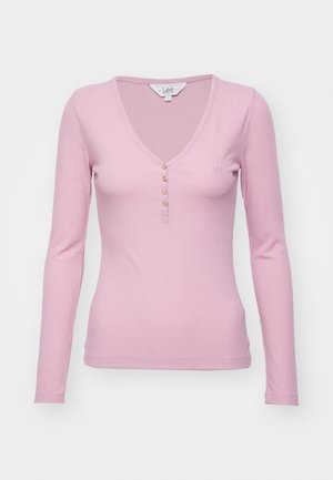 Langermet, ribbestrikket rosa topp med V-hals, med femknapps glidelås og liten brodert logo på brystet.
