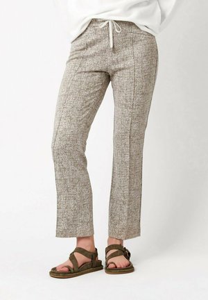 Beige strukturierte, gerade geschnittene Hose in Knöchellänge, getragen mit braunen Riemchensandalen bei einer stehenden Person.