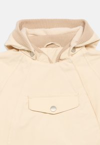 Μπεζ μπουφάν κρεμ χρώματος με μαλακή, ριμπ ύφανση στην εσωτερική επένδυση κουκούλας, κούμπωμα με κλικ και τσέπη στο στήθος. Λείο, ελαφρύ ύφασμα, casual σχέδιο.