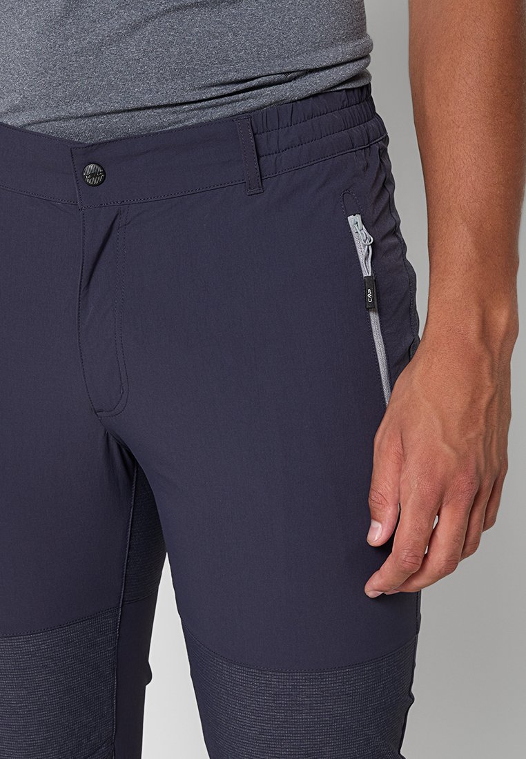Pantalones de exterior para hombre en navy, fabricados con un tejido ligero, que cuentan con una cinturilla elástica, un bolsillo lateral con cremallera y parches texturizados en las piernas inferiores.