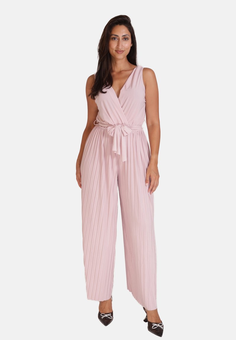 Lichtroze geplooide jumpsuit met een wikkelontwerp en strik taille, voorzien van een diepe V-halslijn en wijd gesneden broekspijpen, aangevuld met zwarte schoenen.
