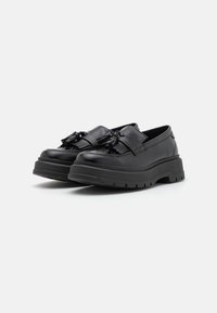 Mustad mustad nahast loafers, millel on paksud kummist tallad, dekoratiivsete tikkide ja sileda viimistlusega. Madala lõikega disain minimaalsetega õmblustega.