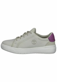 Ljusgrå lädersneaker med en vit gummisula. Har platta skosnören, sidostickningar och en lila detalj på hälen. Timberland-logotyp synlig.