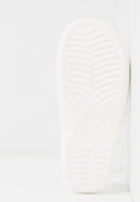 Biała podeszwa Crocs z teksturowanym, wzorzystym uchwytem i wytłoczonym logo. Gładki materiał gumowy z zaokrąglonymi krawędziami i minimalistycznym designem.