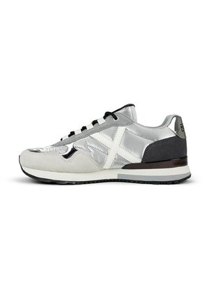 Zapatilla plateada y gris con un upper de ante y metálico, acentos negros, costuras blancas y una suela oscura contrastante. Presenta cordones.