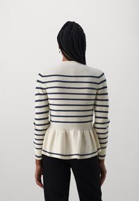 Pull péplum tricoté en crème avec des rayures bleu marine, col rond et manches longues, avec un ourlet évasé et une texture côtelée.