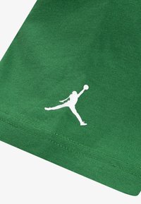 Zaļš kokvilnas T-krekls ar gludu tekstūru un īsām piedurknēm. Uz apakšējās daļas ir balts Jumpman logo.