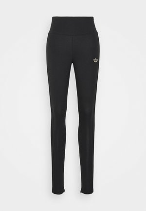 Schwarze Leggings mit Hohe Taille, aus elastischem Stoff gefertigt. Mit einem kleinen goldenen Logo auf der Vorderseite und einer glatten Textur überall.