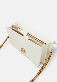 Borsa a mano in pelle bianca con accessori in metallo dorato, scomparto con zip e tracolla a catena. Presenta una texture liscia e un design semplice.