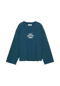 Tyrkysově modrá košile s dlouhým rukávem a širokými rukávy, na přední straně uprostřed je bíle vyvedený text obrácený vzhůru nohama: "VIBES. CULTURE 1991".