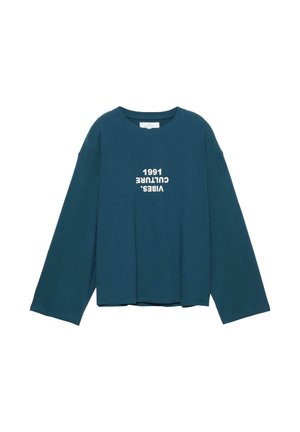 Dolga majica s širokimi rokavi v barvi modrozelene, na sprednji sredini z belim besedilom na glavo: "VIBES. CULTURE 1991".