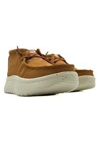 Brown suede shoes with a cream speckled sole, featuring a rounded toe, lace-up design, and textured upper for grip.
