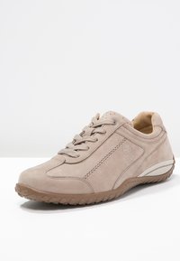 Baskets en daim beige avec bout arrondi, design à lacets, col rembourré et semelle en caoutchouc texturée. Présente un logo sur le côté et des accents cousus.