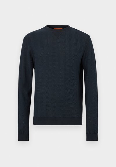 Pull bleu marine à manches longues, motif chevrons texturé, encolure ronde, poignets et ourlet côtelés. Matière en mélange de coton.