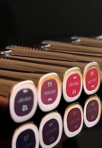 Narzędzia metalowe w kolorze złotym o sześciokątnych kształtach i gładkim wykończeniu są ułożone w rząd, eksponując oznaczenia i liczby z czerwonymi akcentami.