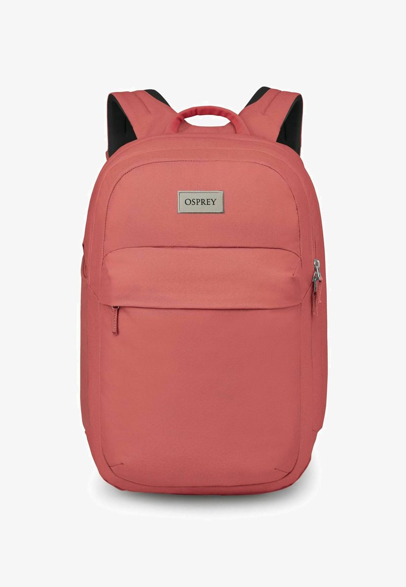 Mochila Osprey en rosa coral. Cuenta con un exterior de tela suave, correas de hombro acolchadas dobles, bolsillo delantero con cremallera y acento de logo.