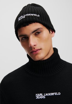 Black ribbed beanie and turtleneck sweater with white "KARL LAGERFELD JEANS" embroidery. The fabric appears thick and textured.