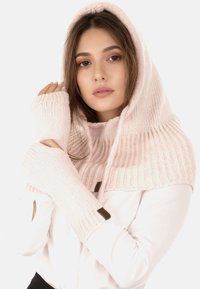 Vaaleanpunainen neulehuppari ja sormettomat hanskat, joissa on ribbaustekstuuri ja nahka-akcentit. Pehmeä, mukava materiaali, joka on suunniteltu lämpöä varten.