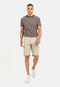 Gestreepte T-shirt met korte mouwen in marineblauw, rood en wit; gecombineerd met beige cargoshorts; witte sneakers maken de casual outfit compleet.