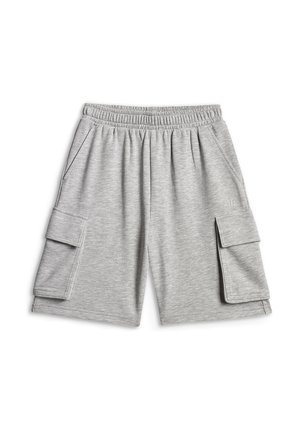 Chłopiec w szarej luźnej koszulce i szortach, białe sportowe buty, niebieska bluza zarzucona na ramiona, trzyma małą beżową torbę za czarny pasek.