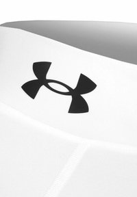 Canotta sportiva bianca con un prominente logo Under Armour nero. Tessuto liscio con design senza cuciture e forma aderente.