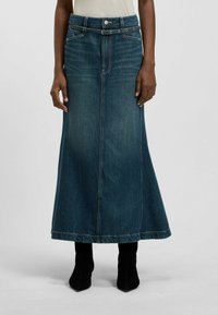 Tummansininen farkkumallinen maksihame liehuvilla saumoilla, jossa on napitus, vyön lenkit ja sivutaskut. Yhdistetty mustiin nilkkureihin.