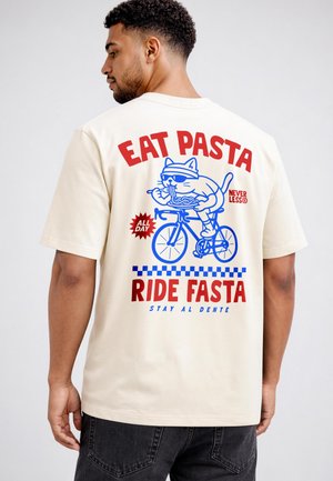 Mann trägt cremefarbenes Hemd mit einer Grafik einer Katze, die Pasta isst und Fahrrad fährt, der Text lautet „Iss Pasta, fahr schnell, bleib al dente.“