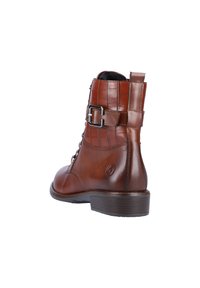 Bottine en cuir marron avec un motif gaufré crocodile, système de laçage, boucle sur le côté et un petit talon empilé. Elle possède une doublure douce.
