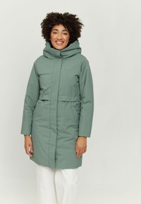 Long, green puffer coat with a high collar, wide hood, and front pockets. Smooth texture, cinched waist detail, and minimal branding.