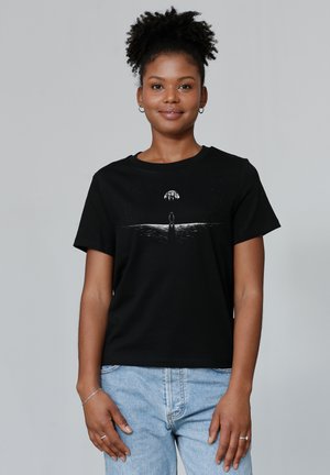 Zwart T-shirt met korte mouwen, met een witte grafische afbeelding van een figuur met een maan boven water. Van zachte katoen.