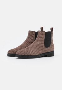 Bottines Chelsea en suède tissé marron avec des panneaux élastiques noirs sur les côtés et des tirants à l'arrière. Surface texturée, bout rond, petit talon empilé.