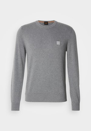 Suéter de cuello redondo gris de manga larga para hombre, con puños y dobladillo acanalados, que presenta un pequeño parche de logo cuadrado en el lado izquierdo del pecho.