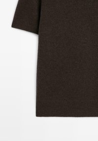 Brunstickad plagg med korta ärmar, som har en mjuk textur och en rak fåll. Materialet verkar lätt och varmt.