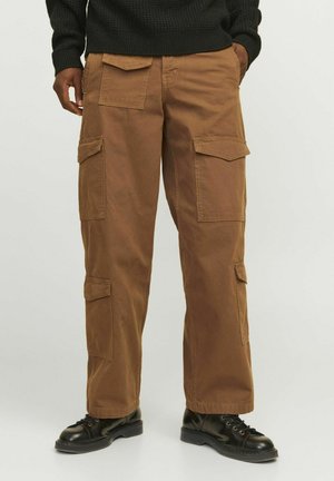 Cargo pants in brown cotton material, featuring multiple pockets, a relaxed fit, and a straight leg design. Styled with black boots.