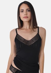Black tank top featuring a lace trim along the v-neckline, made from a textured fabric with subtle vertical stripes and adjustable straps.