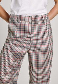 Kárované kalhoty v béžové, červené a modré barv�ě; mají přiléhavý střih, sklady a boční kapsy; vyrobeny z tkané látky.