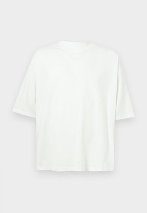 Läbimõõduga valge lühikese varrukaga t-särk klassikalise kaelusega, tasapinnal helehalli tausta peal.