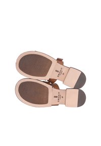 Bruine leren sandalen met platte zolen, voorzien van een gestructureerd patroon en twee banden. De binnenkant heeft een reliëf met merk- en maatgegevens.