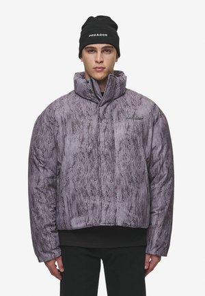 Puffer jacket in textured lavender fabric with a high collar, featuring subtle patterns and a front zipper. Paired with a black beanie.