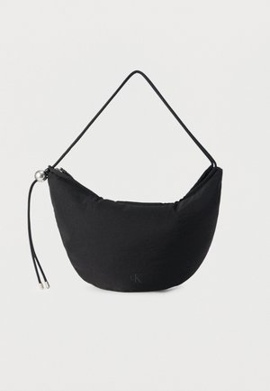 Czarna materiałowa torba o półksiężycowym kształcie, z cienkim uchwytem, zamkiem błyskawicznym i ozdobnym metalowym elementem. Na przodzie znajduje się małe logo.