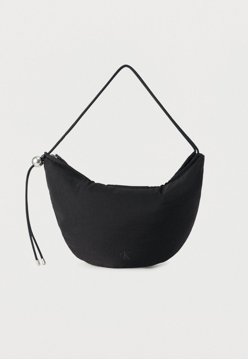 Μαύρη υφασμάτινη τσάντα με ημικυκλικό σχήμα, λεπτή λαβή, κλείσιμο με φερμουάρ και διακοσμητικά μεταλλικά στοιχεία. Διαθέτει μικρό λογότυπο στο μπροστινό μέρος.