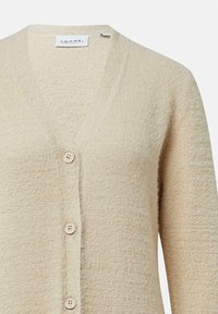 Cardigan in maglia beige con scollo a V, dotato di cinque bottoni, tessuto testurizzato e vestibilità comoda, ideale da sovrapporre in vari outfit.